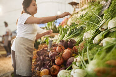 Woman working, arranging produce at farmer’s market - CAIF24622