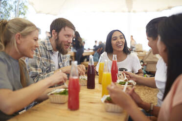 Lächelnde Freunde beim Mittagessen auf dem Bauernmarkt - CAIF24637