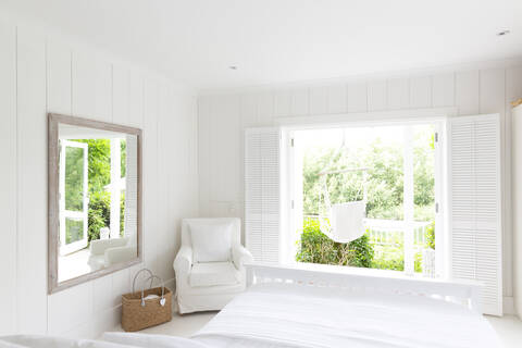 Weißes, ruhiges Musterhaus mit Schlafzimmer, das zur sonnigen Terrasse mit Hängematte führt, lizenzfreies Stockfoto