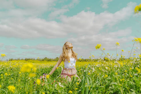 Junge Frau auf einer Blumenwiese im Frühling - ERRF02894