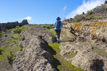 Spanien, Provinz Santa Cruz de Tenerife, San Sebastian de La Gomera, Rückansicht eines älteren Rucksacktouristen beim Wandern auf einem felsigen Pfad - SIEF09669
