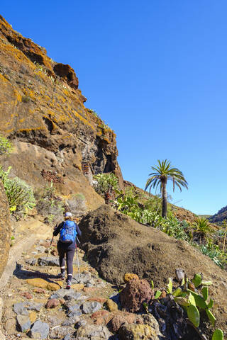 Spain, Province of Santa Cruz de Tenerife, San Sebastian de La Gomera, Rear view of senior backpacker hiking along rocky hillside at Alto de Tacalcuse stock photo