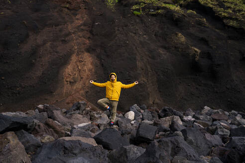 Man standing amidst volcanic rocks in yoga pose, Sao Miguel Island, Azores, Portugal - AFVF05834