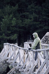 Lonely man standing on wooden bridge through he forest, Bulgaria - BZF00535