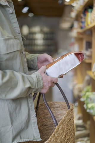 Nahaufnahme eines älteren Mannes, der in einem kleinen Lebensmittelladen Lebensmittel einkauft und die Zutaten überprüft, lizenzfreies Stockfoto