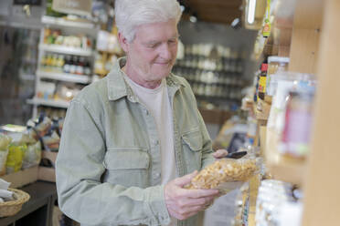 Älterer Mann kauft in einem kleinen Lebensmittelgeschäft Lebensmittel ein - AFVF05848