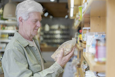 Älterer Mann kauft in einem kleinen Lebensmittelgeschäft Lebensmittel ein - AFVF05849