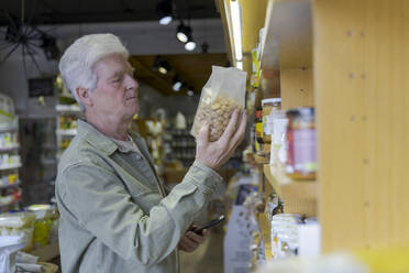 Älterer Mann kauft in einem kleinen Lebensmittelgeschäft Lebensmittel ein - AFVF05858