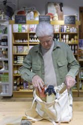Älterer Mann kauft in einem kleinen Lebensmittelgeschäft Lebensmittel ein - AFVF05868