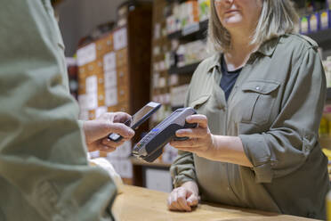 Kunde zahlt kontaktlos mit Smartphone in einem Geschäft - AFVF05872