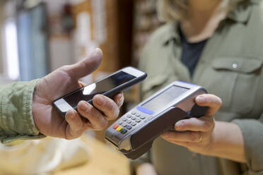 Customer paying contactless with smartphone in a shop - AFVF05873