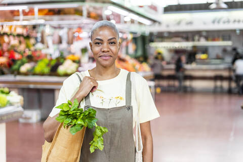 Portrait of smiling woman buying groceries in a market hall stock photo