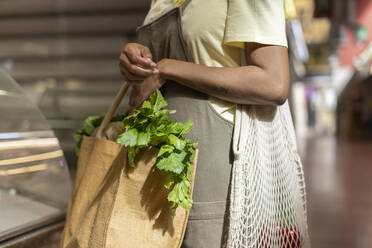Mittelteil einer Frau beim Lebensmitteleinkauf in einer Markthalle - AFVF05906