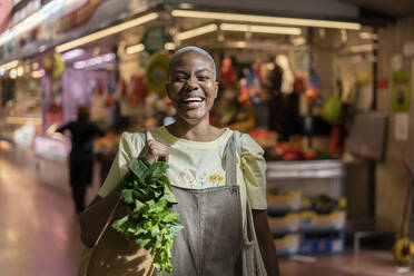 Portrait of happy woman buying groceries in a market hall - AFVF05908