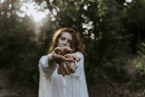 Junge rothaarige Frau streckt ihre Hände im Wald aus - AFVF05924