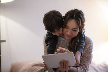 Mother and little son using digital tablet at home - KNSF07939