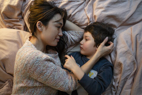 Mother and little son relaxing together on bed stock photo