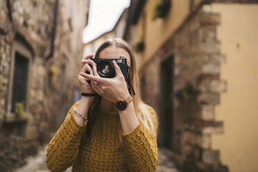Junge Frau beim Fotografieren mit einer altmodischen Kamera in der Altstadt von Greve in Chianti, Toskana, Italien - JPIF00565