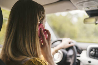 Rückansicht einer jungen Frau beim Telefonieren im Auto - JPIF00569