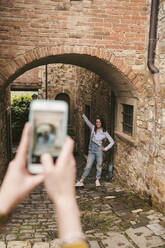 Woman taking a picture of her friend in picturesque old town, Greve in Chianti, Tuscany, Italy - JPIF00571