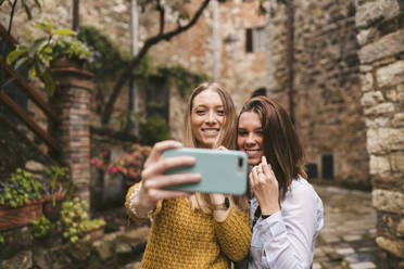 Zwei junge Frauen machen ein Selfie in der malerischen Altstadt von Greve in Chianti, Toskana, Italien - JPIF00573