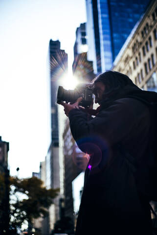 USA, New York City, Junger Mann beim Fotografieren mit seiner Kamera, lizenzfreies Stockfoto