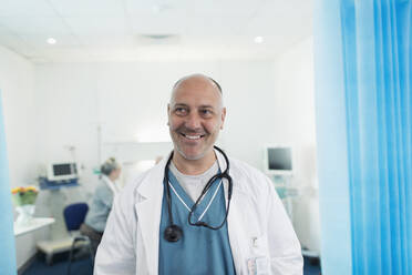 Porträt eines selbstbewussten, lächelnden Arztes in einem Krankenhauszimmer - CAIF24736