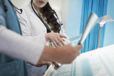 Doctors with digital tablet discussing x-ray in hospital room - CAIF24739