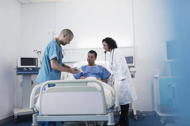 Arzt und Krankenschwester mit digitalem Tablet bei der Visite, Gespräch mit Patient im Krankenhauszimmer - CAIF24741