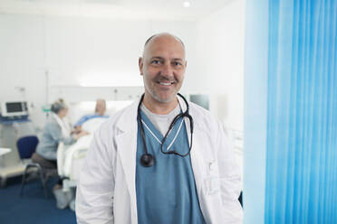 Porträt eines selbstbewussten, lächelnden Arztes in einem Krankenhauszimmer - CAIF24756