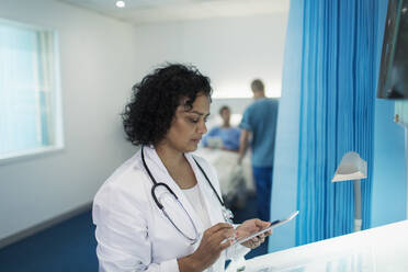 Fokussierte Ärztin mit digitalem Tablet im Krankenhauszimmer - CAIF24766