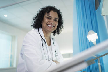 Porträt einer selbstbewussten, lächelnden Ärztin in einem Krankenhauszimmer - CAIF24772