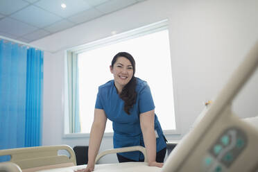 Porträt einer selbstbewussten, lächelnden Krankenschwester, die ein Krankenhausbett macht - CAIF24779