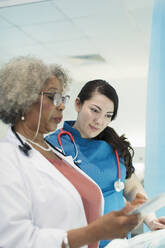Ärztin und Krankenschwester mit digitalem Tablet im Gespräch im Krankenhaus - CAIF24780