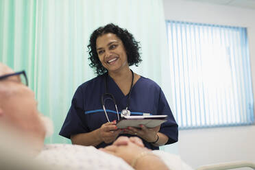 Krankenschwester mit digitalem Tablet bei der Visite, Gespräch mit Patient im Krankenhauszimmer - CAIF24782