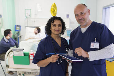 Porträt selbstbewusster Ärzte mit digitalem Tablet bei der Visite im Krankenhauszimmer - CAIF24789