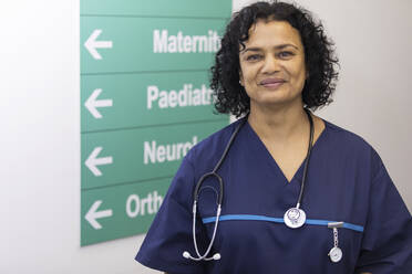 Porträt einer selbstbewussten Ärztin in einem Krankenhauskorridor - CAIF24824