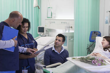 Ärzte mit Krankenblatt bei der Visite, Gespräch mit Ehepaar auf der Krankenstation - CAIF24825