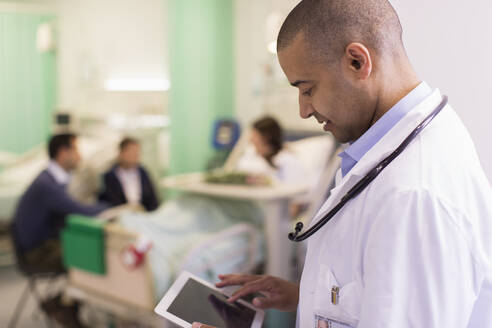 Männlicher Arzt mit digitalem Tablet bei der Visite in einer Krankenstation - CAIF24827