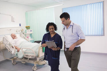 Ärzte mit digitalem Tablet bei der Visite, Beratung im Krankenhauszimmer - CAIF24872