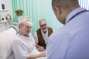 Arzt auf Visite, Gespräch mit älterem Ehepaar im Krankenhauszimmer - CAIF24878