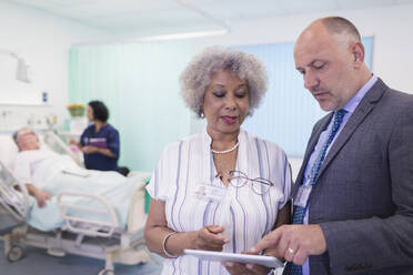 Ärzte mit digitalem Tablet bei der Visite, Beratung im Krankenhauszimmer - CAIF24885