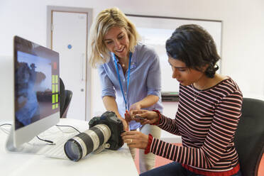 Female photographer teaching student how to use SLR camera - CAIF24887