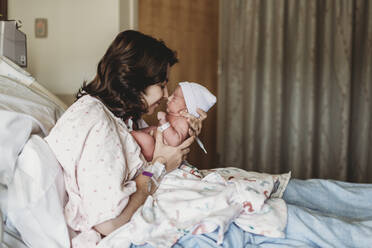 Side view of mother and newborn son touching noses in hospital - CAVF77657