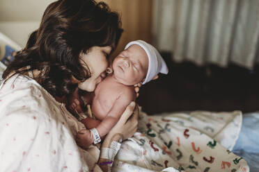 Close up detail of mother kissing newborn son in hospital - CAVF77663