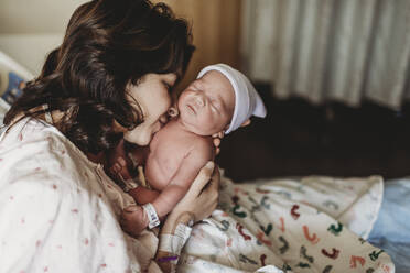 Nahaufnahme einer Mutter, die ihren neugeborenen Sohn im Krankenhaus küsst - CAVF77663