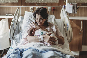 Mid view of mother in hospital bed looking at newborn son - CAVF77669