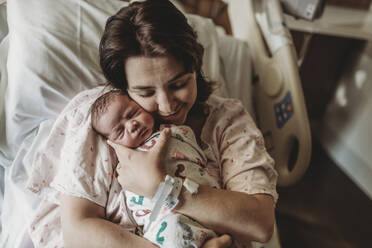 Mid view of mother in hospital bed looking at newborn son - CAVF77671