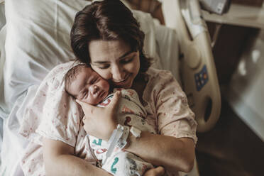 Mittelansicht einer Mutter im Krankenhausbett mit Blick auf ihren neugeborenen Sohn - CAVF77671