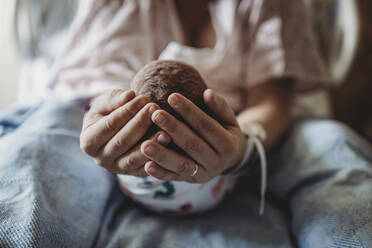 Makroansicht der Hände der Mutter, die den Kopf des neugeborenen Jungen halten - CAVF77672